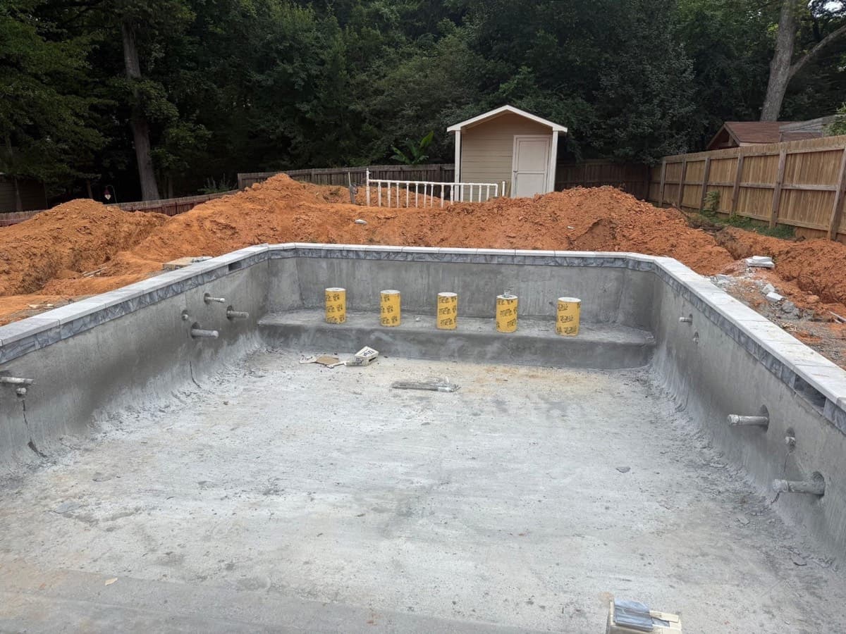 Empty pool shell with earth stockpiled around the site