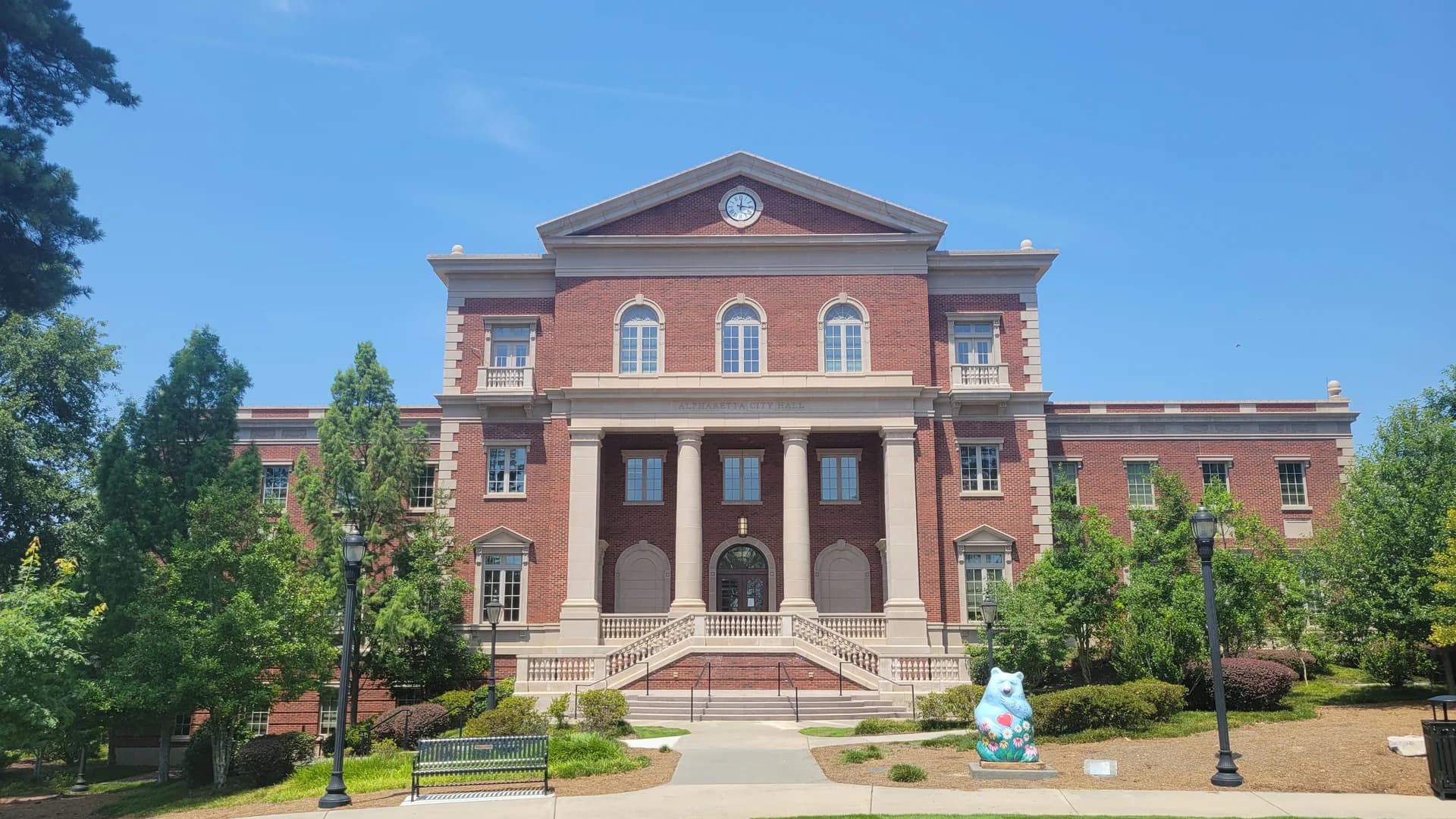 Alpharetta City Hall’s brick facade, clock and columns viewed from Brooke Street Park in Alpharetta, Georgia.