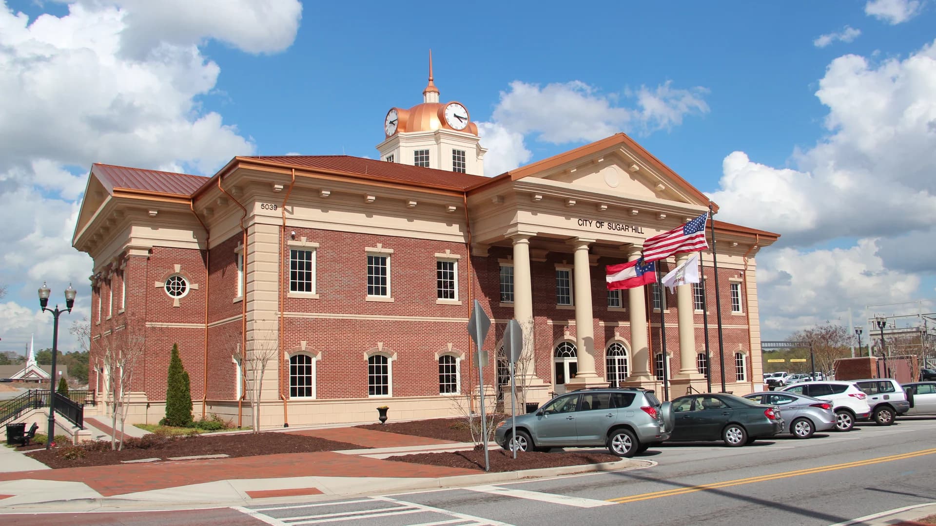 Sugar Hill City Hall with its clock tower and flags in Sugar Hill, Georgia.